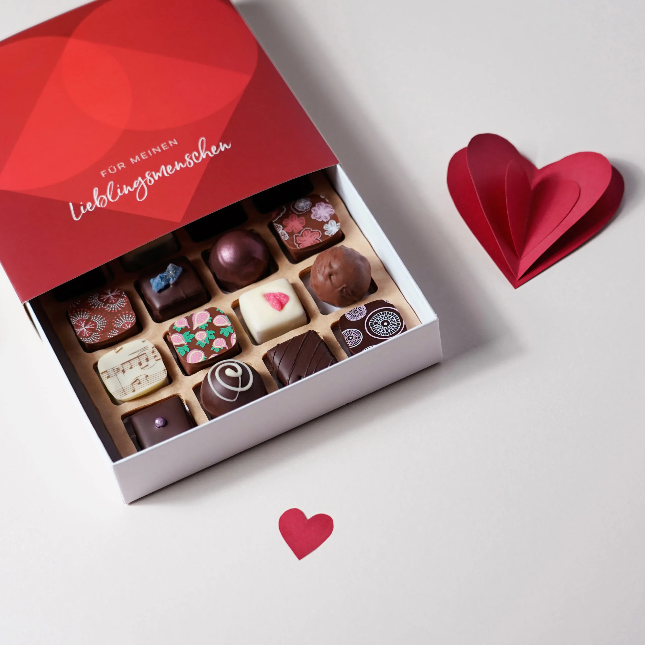 Pralinenbox mit 16 Pralinen und der roten Banderole 