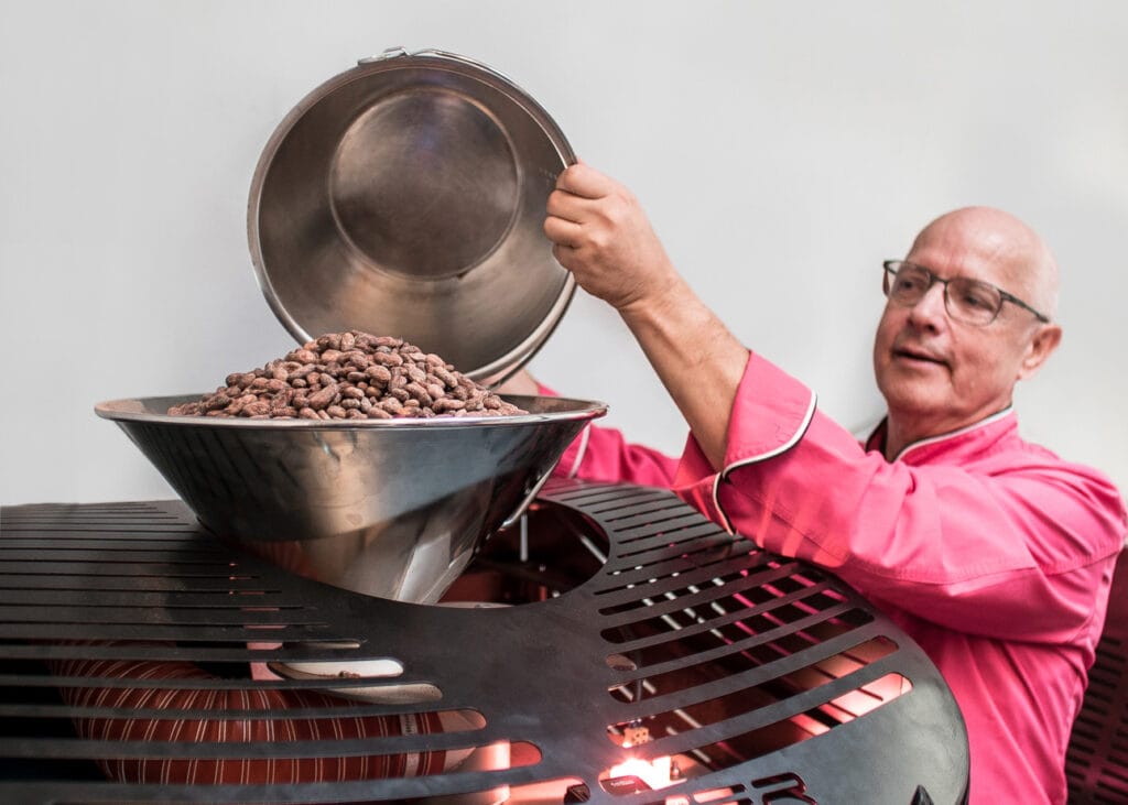 Bean to Bar Schokoladen Produktion. Chefchocolatier Manfred Glatzel beim Einfüllen von Kakaobohnen in den Röster