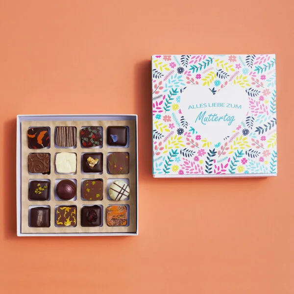 Pralinenbox mit 'Alles Liebe zum Muttertag' Motiv mit Blumen und Herz in blau, gelb und pink. Daneben die geöffnete Box mit 16 bunt dekorierten Pralinen.