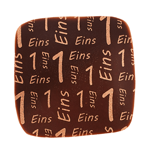 Eckige Praline mit dunkler Milchschokolade überzogen und mit einem Kupferfarbenen Print mit der Zahl und dem Wort eins