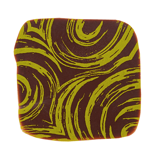 Eckige Praline mit dunkler Schokolade überzogen, bedruckt mit einem unregelmäßigen Muster aus grünen Wirbeln