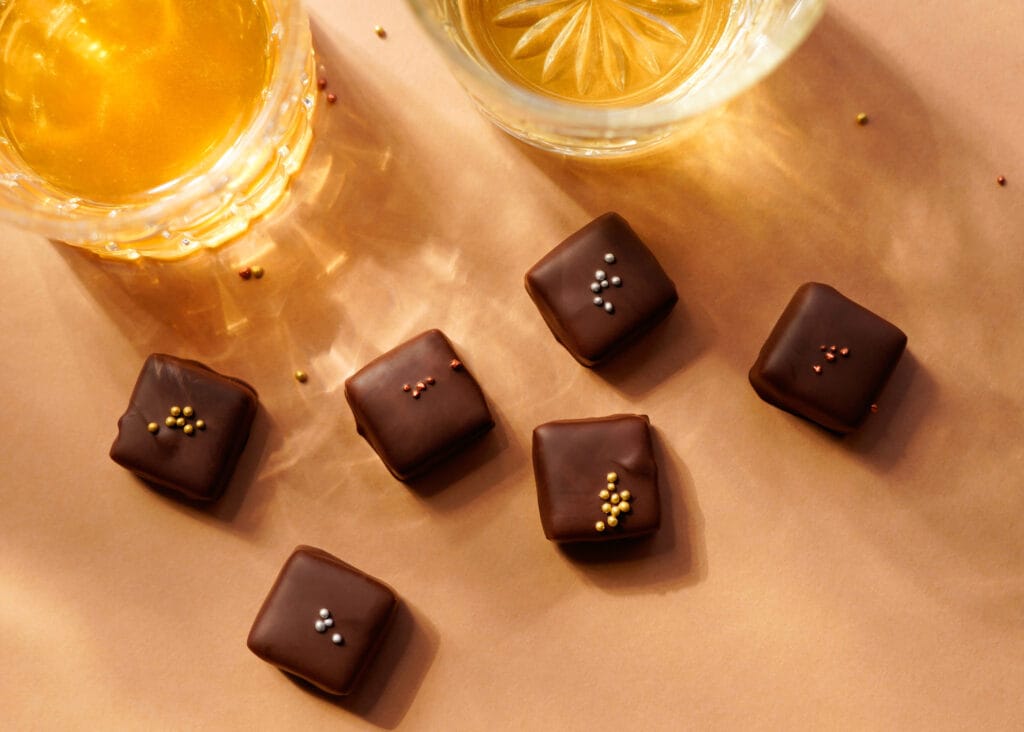 Pralinen von oben, neben zwei mit Whisky gefüllten Gläsern.