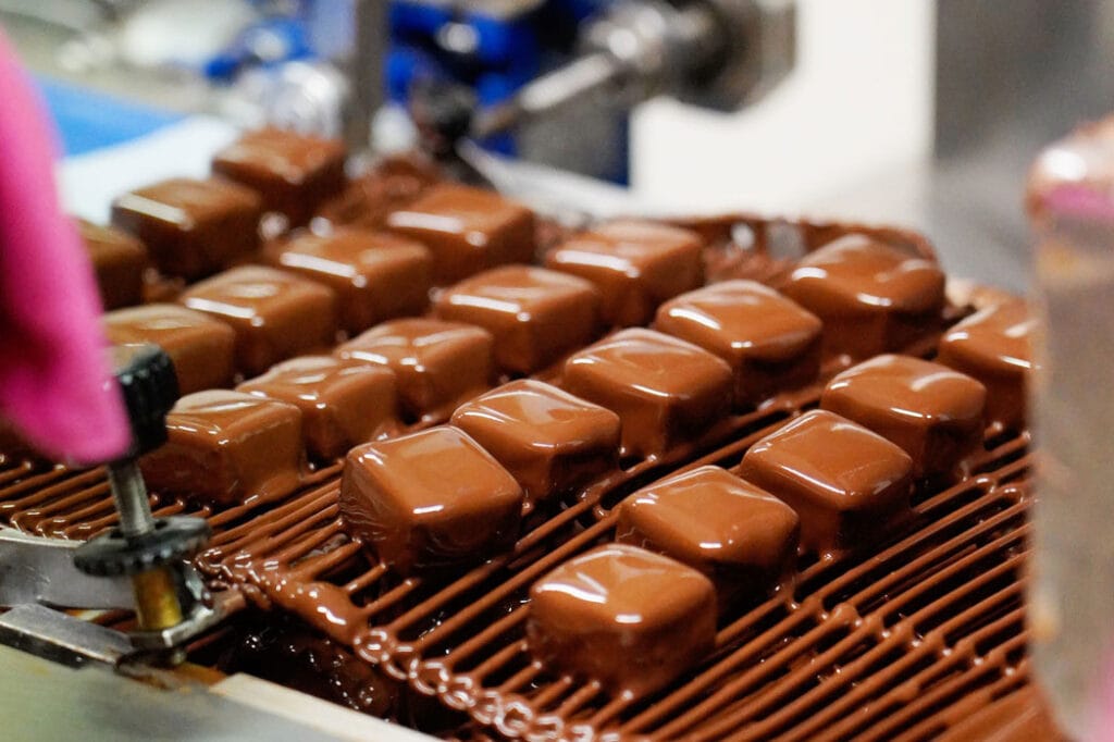 Pralinen werden mit Schokolade überzogen