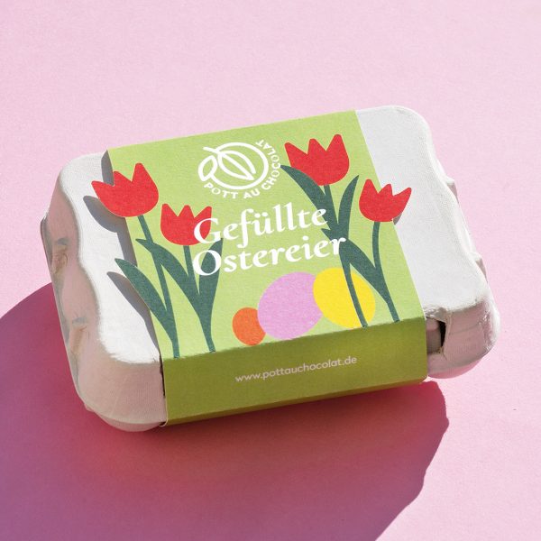 Eierkarton mit Banderole in hellgrün mit bunten Blumen und Ostereiern. Logo von Pott au Chocolat und 'Gefüllte Ostereier'