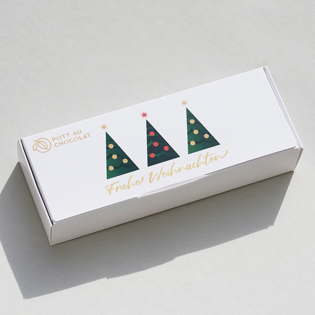 Weiße Pralinenschachtel mit Aufschrift 'Frohe Weihnachten' mit 3 dekorierten Weihnachtsbäumen.
