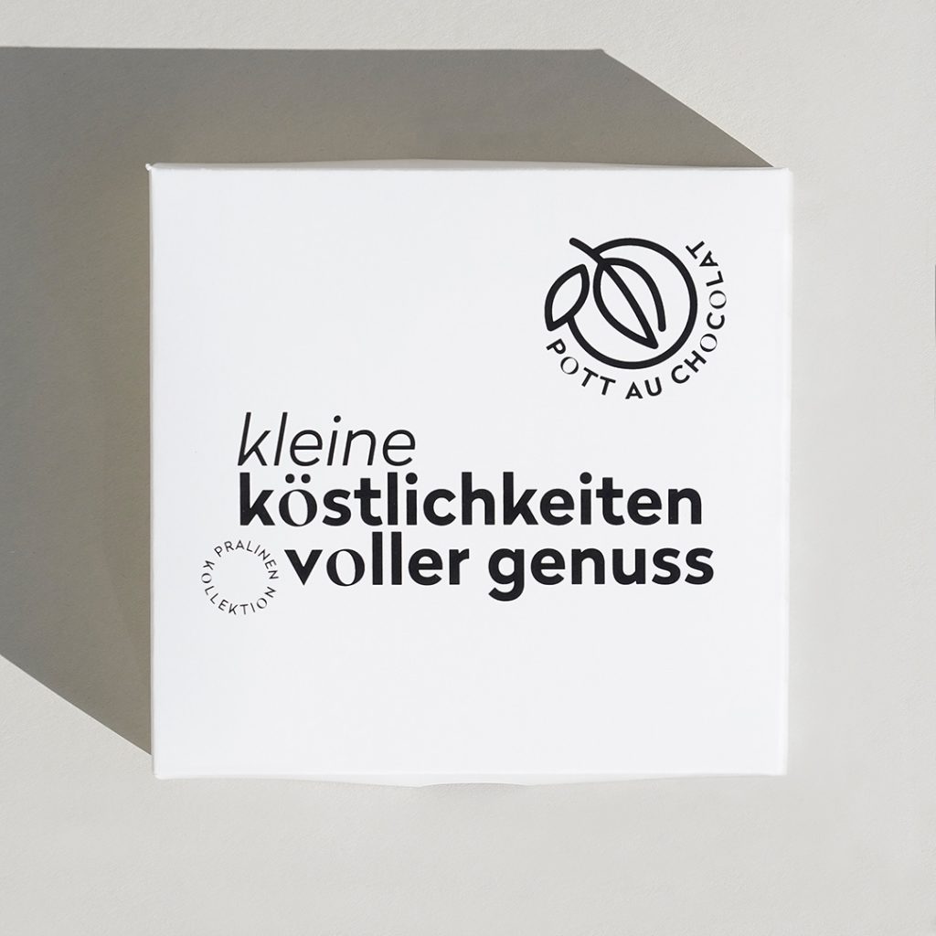 Weiße Pralinenschachtel mit der Aufschrift 'Kleine Köstlichkeiten voller Genuss' und dem Logo von Pott au Chocolat. Die Schachtel kann personalisiert werden.