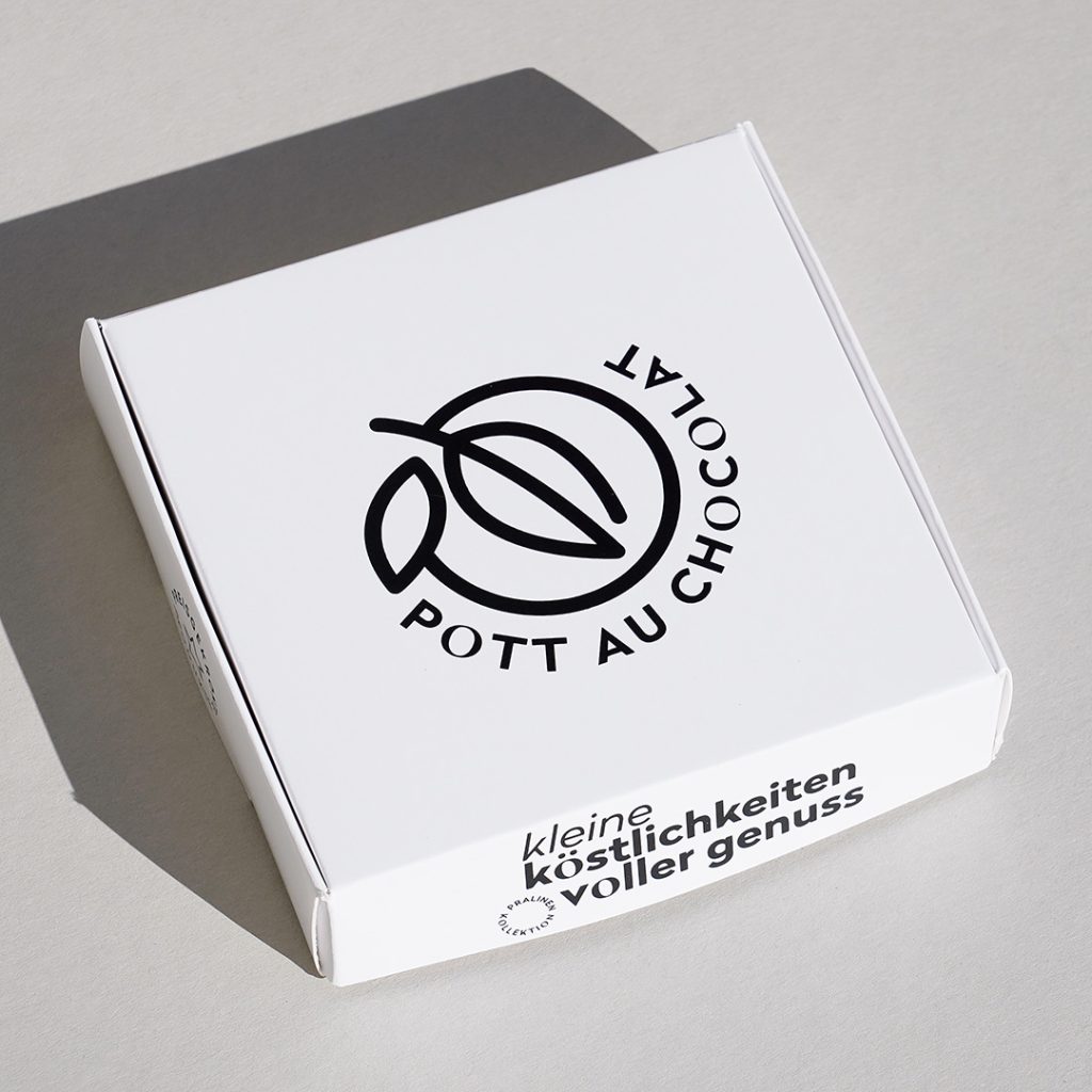 Weiße Pralinenschachtel mit Logo von Pott au Chocolat und der Aufschrift 'Kleine Köstlichkeiten voller Genuss'.