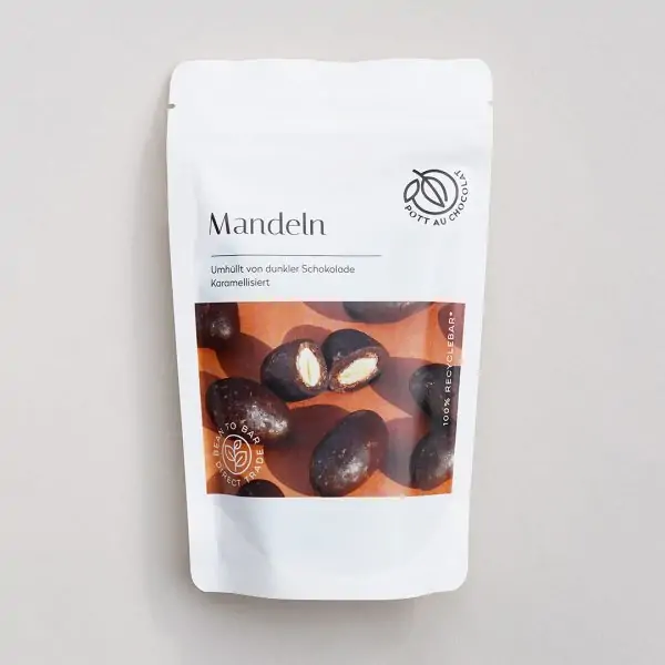 Verpackung Vorderseite der karamellisierten Mandeln in dunkler Schokolade. Weiße PET Tüte mit Foto der Mandeln.