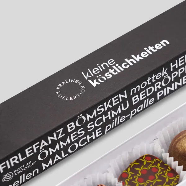 Detail der Pralinenstange Ruhrgebiet. 'Kleine Köstlichkeiten' auf schwarzem Hintergrund. Am Rand verschiedene typische Ruhrgebiets Wörter.