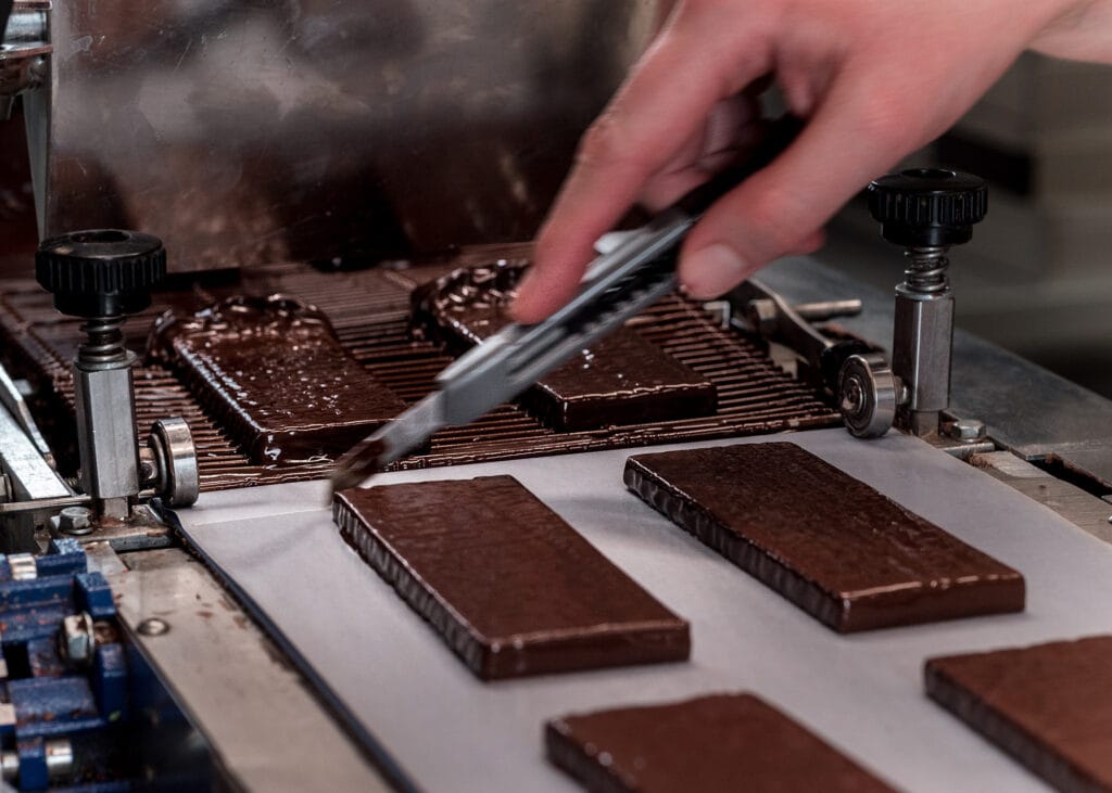 In der Produktion: Frisch überzogene Schokoladentafeln liegen auf einem Band