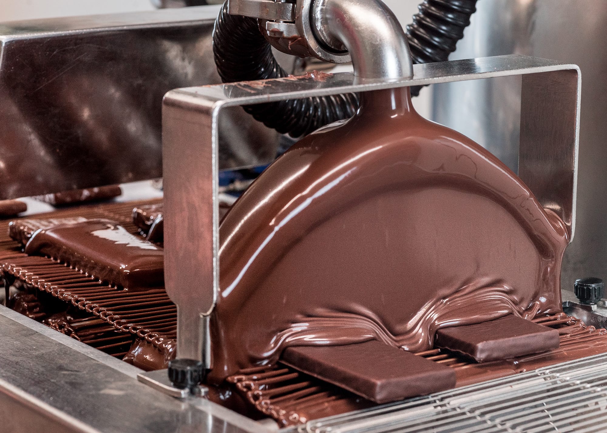 Schokoladentafeln werden mit einer Maschine mit Schokolade überzogen