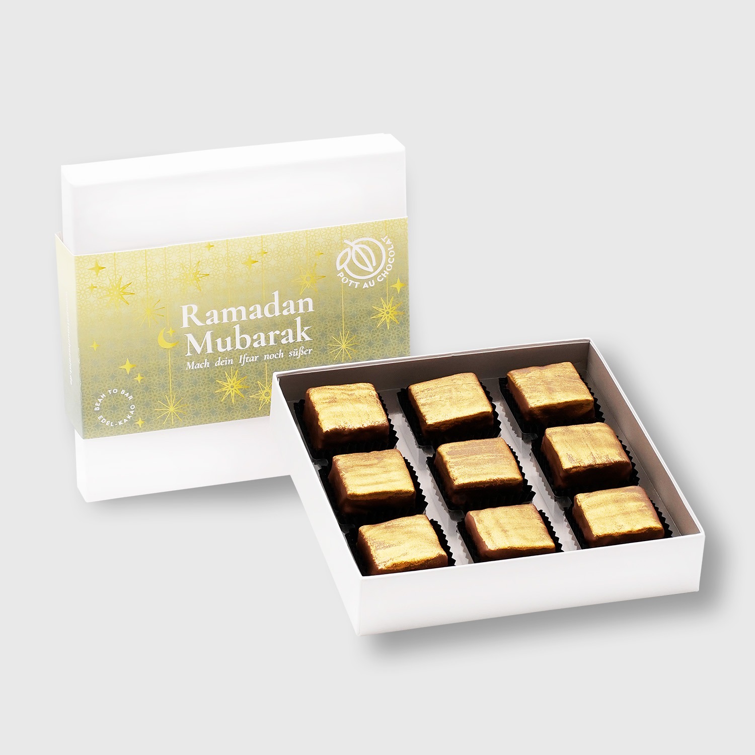Geschlossene und geöffnete Schachtel für Ramadan Mubarak Iftar Kuchen. Banderole in gelb und grün mit Sternen und Mond. In der geöffneten Packung 9 kleine eckige Kuchen mit Schokolade überzogen und gold angesprüht.