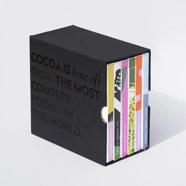 Unsere Mix and Match Chocolate Gift Box - 6 bunte Schokoladentafeln verpackt in einem schwarzen Schuber aus Pappe, der mit schwarzer Schrift geprägt wurde. Der Text ist englisch und der Inhalt: Kakao ist eines der komplexesten Lebensmittel der Welt.