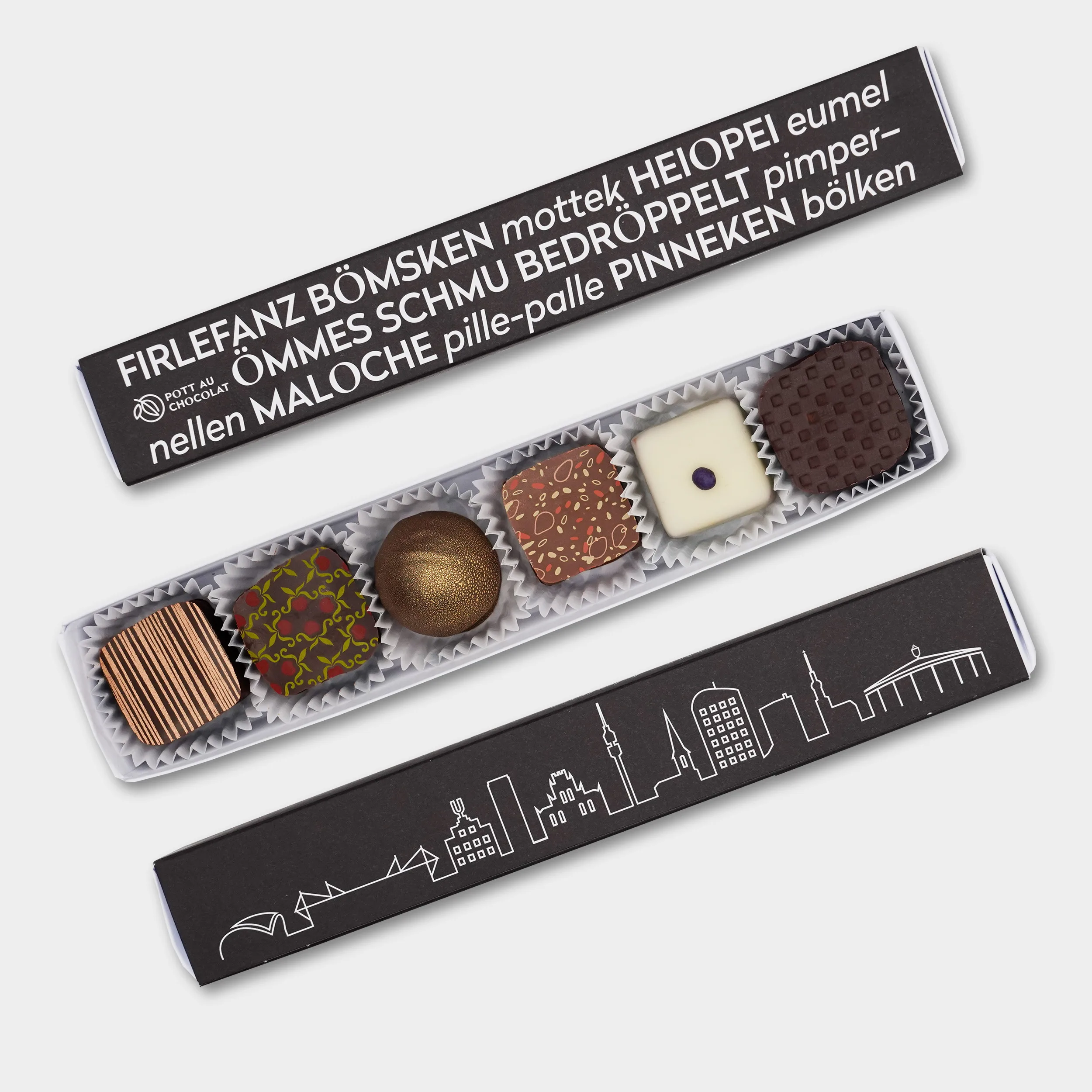 Pralinen Stange in schwarz mit Skyline von Dortmund und Ruhrgebiet Wörtern, wie 'Filefanz, Heiopei, pille-palle' und weiteren. Davor eine geöffnete Pralinenstange mit 6 bunt dekorierten Pralinen.