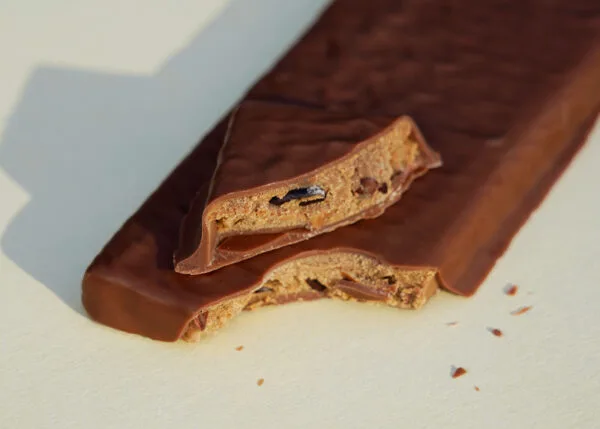 Gefüllte Tafel ohne Verpackung, angeschnitten, sodass die Nougat-Kakaosplitter-Füllung sichtbar ist