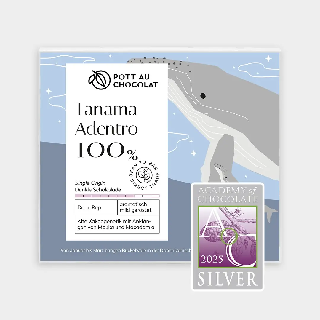 Verpackung der Tafel Tanama Adentro 100% mit einem Motiv in hellen Blau- und Grautönen mit einem Wal im Meer. Abgebildet ist außerdem eine Auszeichnung von der Academy of Chocolate 2025, Silber .