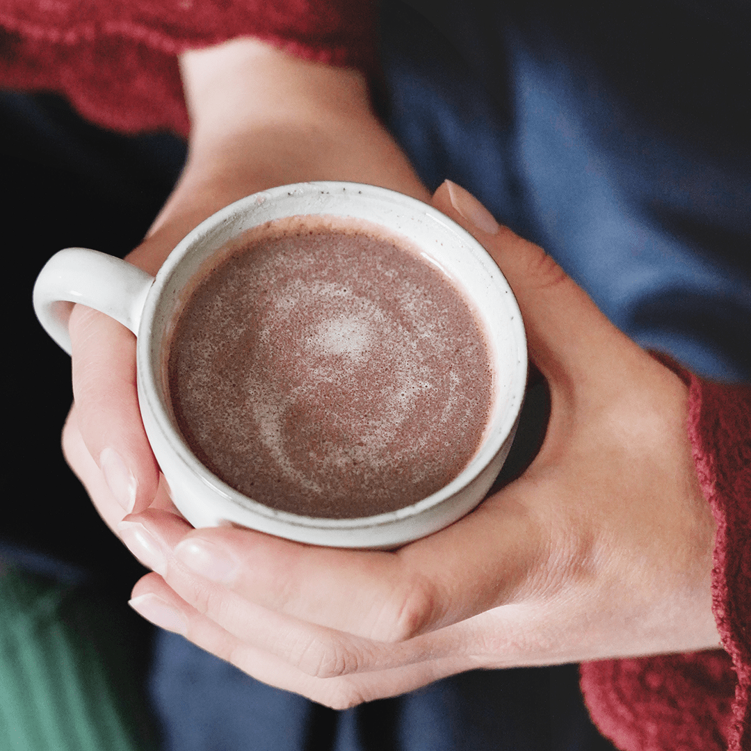 Zwei Hände halten eine Tasse mit Trinkschokolade.