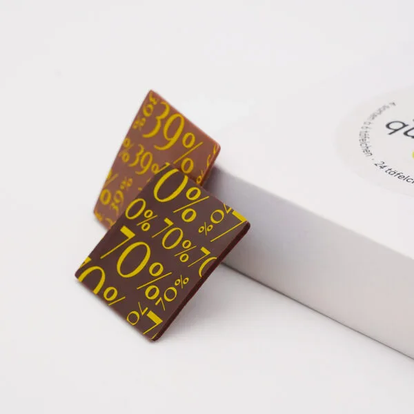Genuss-Quartett mit 4 verschiedenen Täfelchen Schokolade. Nahaufnahme von zwei Täfelchen, die gegen die Verpackung gelehnt sind