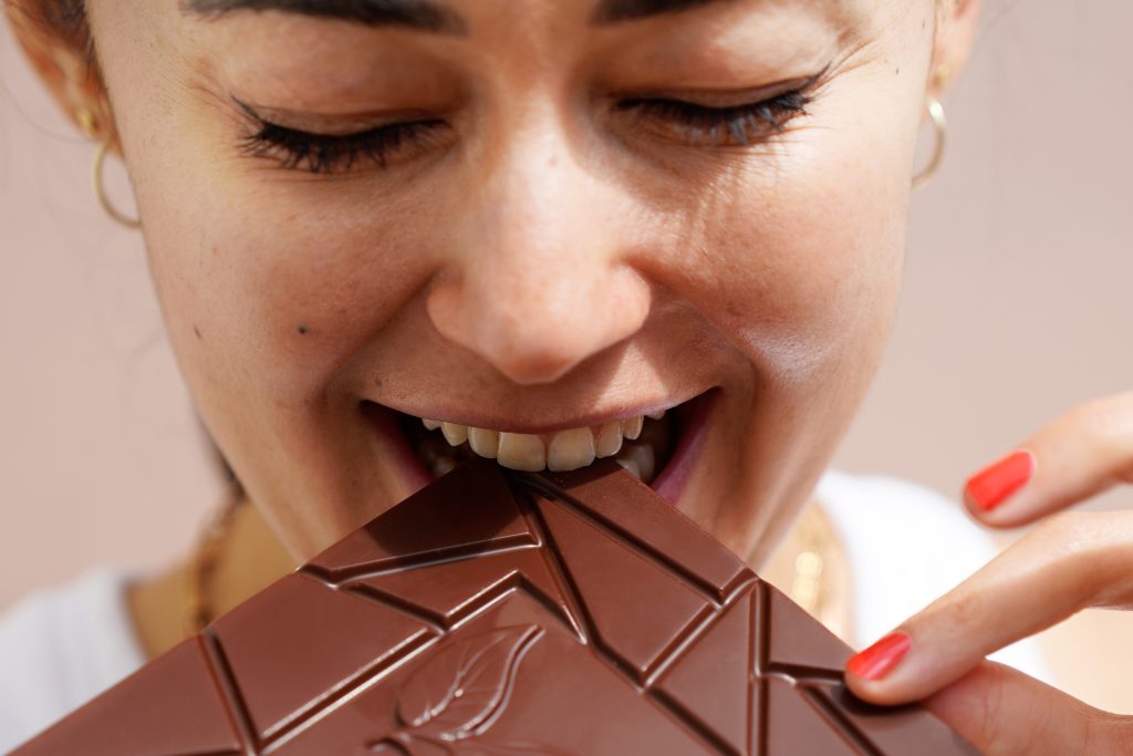 Thema Geschmack: Frau beißt in eine Schokoladentafel von Pott au Chocolat (Nahaufnahme).