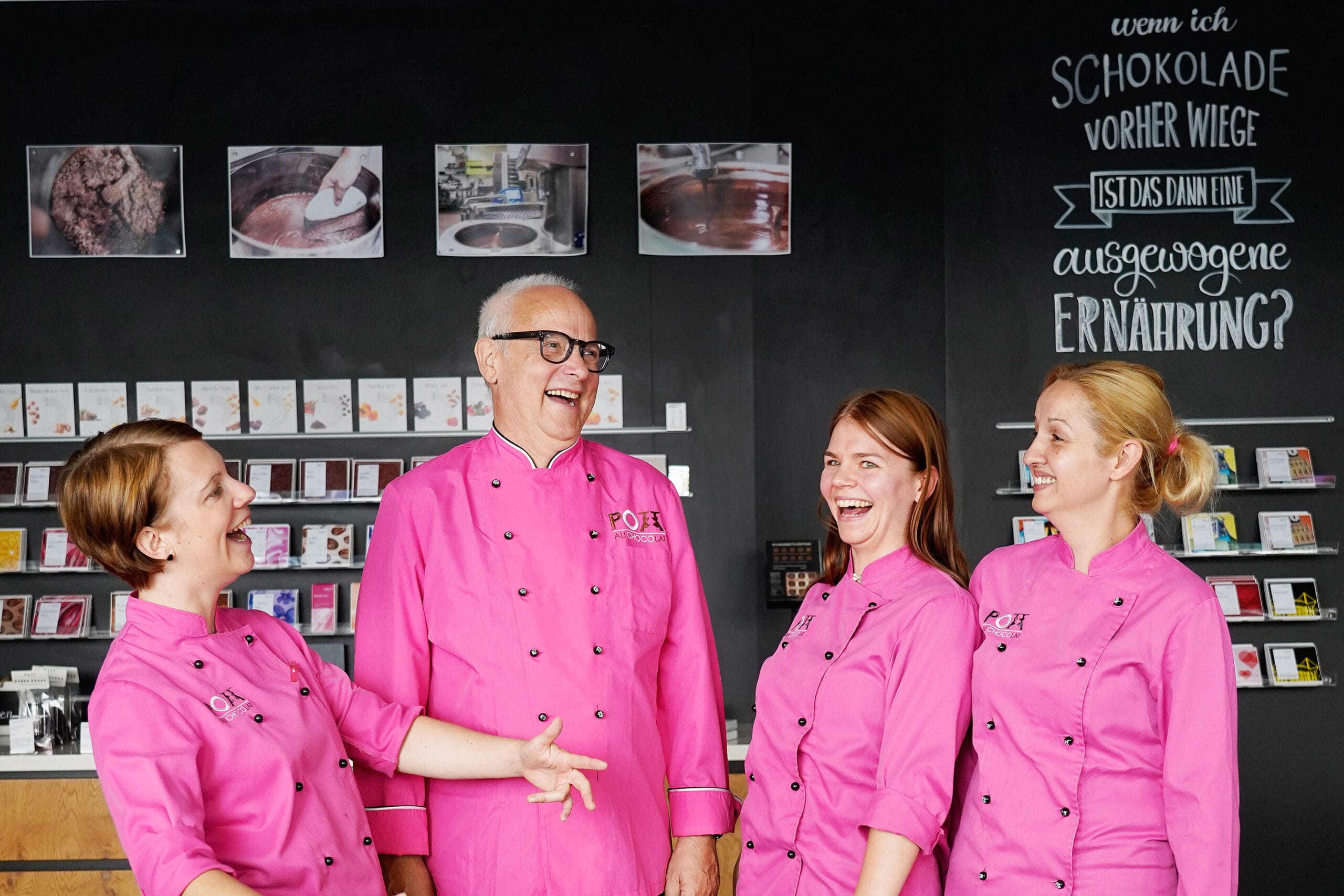 Produktionsteam in pinken Oberteilen – ein Mann und drei Frauen lachen gemeinsam