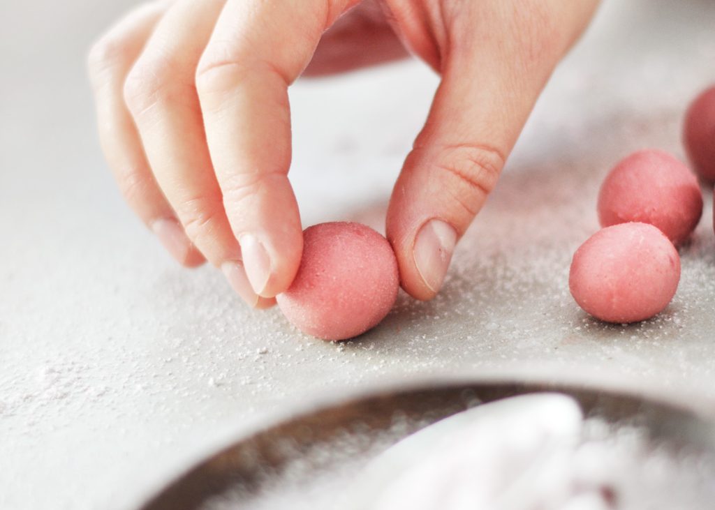 Ein frischer Trüffel in rosa wird von Hand gerollt