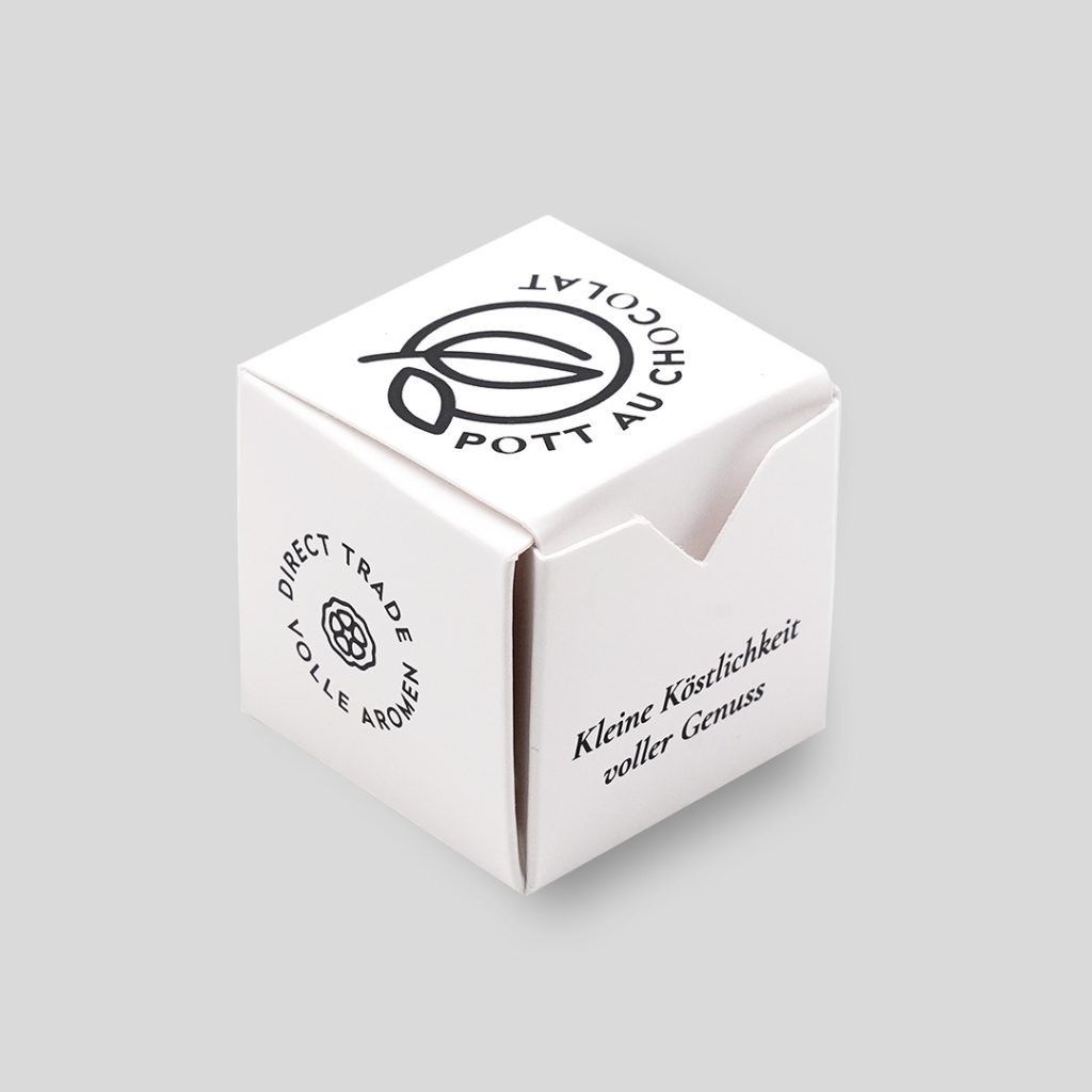 Kleine Schachtel für 1 Praline in Würfel-Form. Weißer Karton mit schwarzen Illustrationen und Logo von Pott au Chocolat bedruckt.