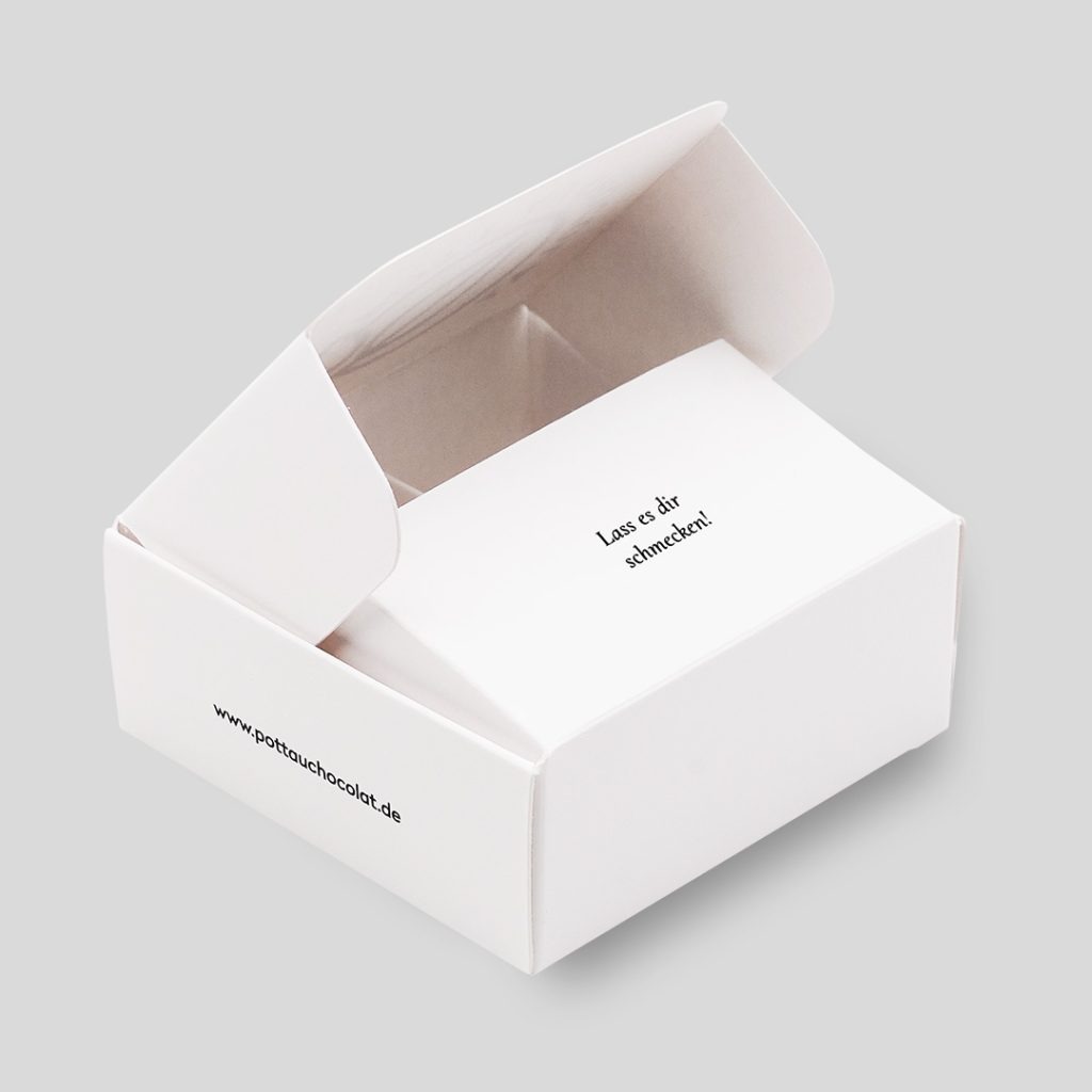 4er Pralinen Schachtel aus weißem Karton mit schwarzem Logo von Pott au Chocolat. Die Schachtel ist leicht geöffnet.