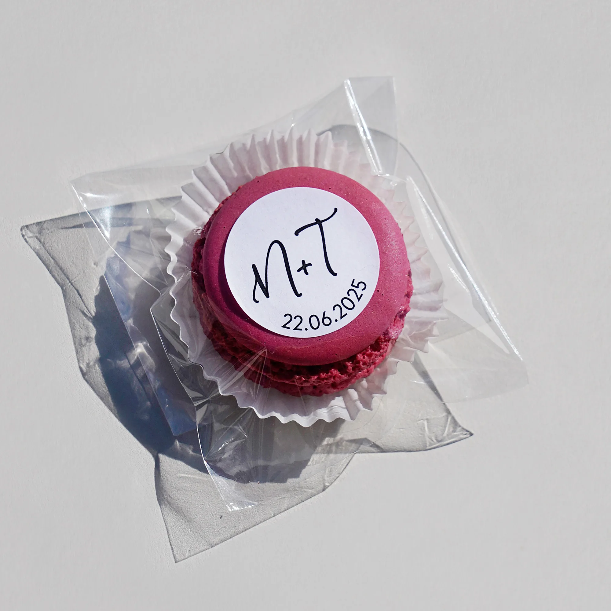 Macaron im transparenten Tütchen verpackt und als Beispiel individualisiert mit einem runden Etikett mit den Anfangs Buchstaben und einem Datum