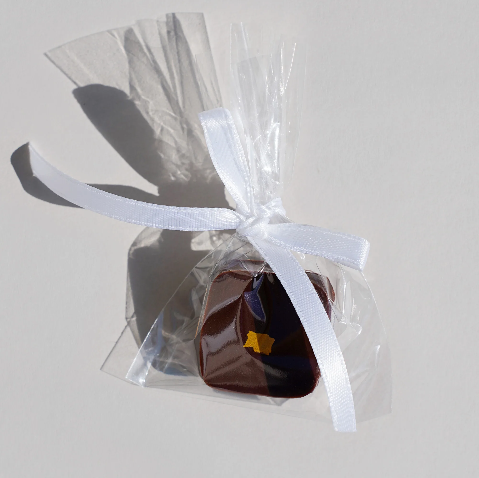 Eine Schokomousse Praline im Tütchen mit einer weißen Schleife als Beispiel für eine Hochzeitsdekoration