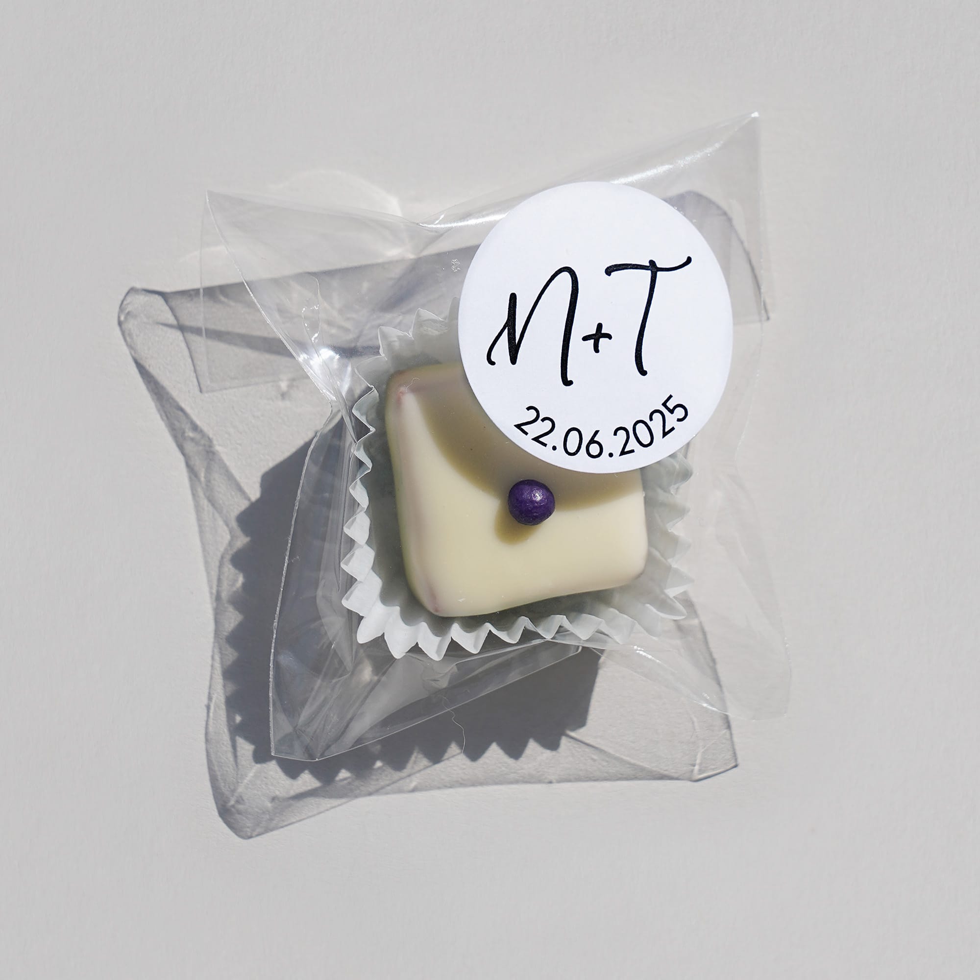 eine Praline im Tütchen mit weissem Überzug versehen mit einem individualisierten runden Etikett
