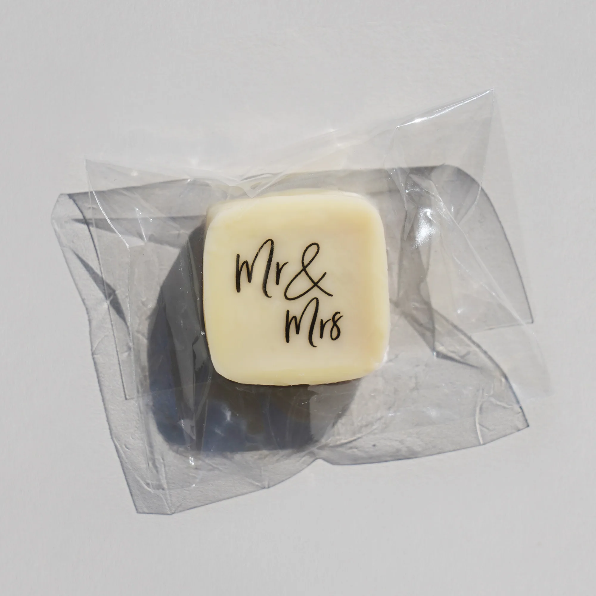 eine Praline im Tütchen mit weißem Überzug und einem Aufdruck
