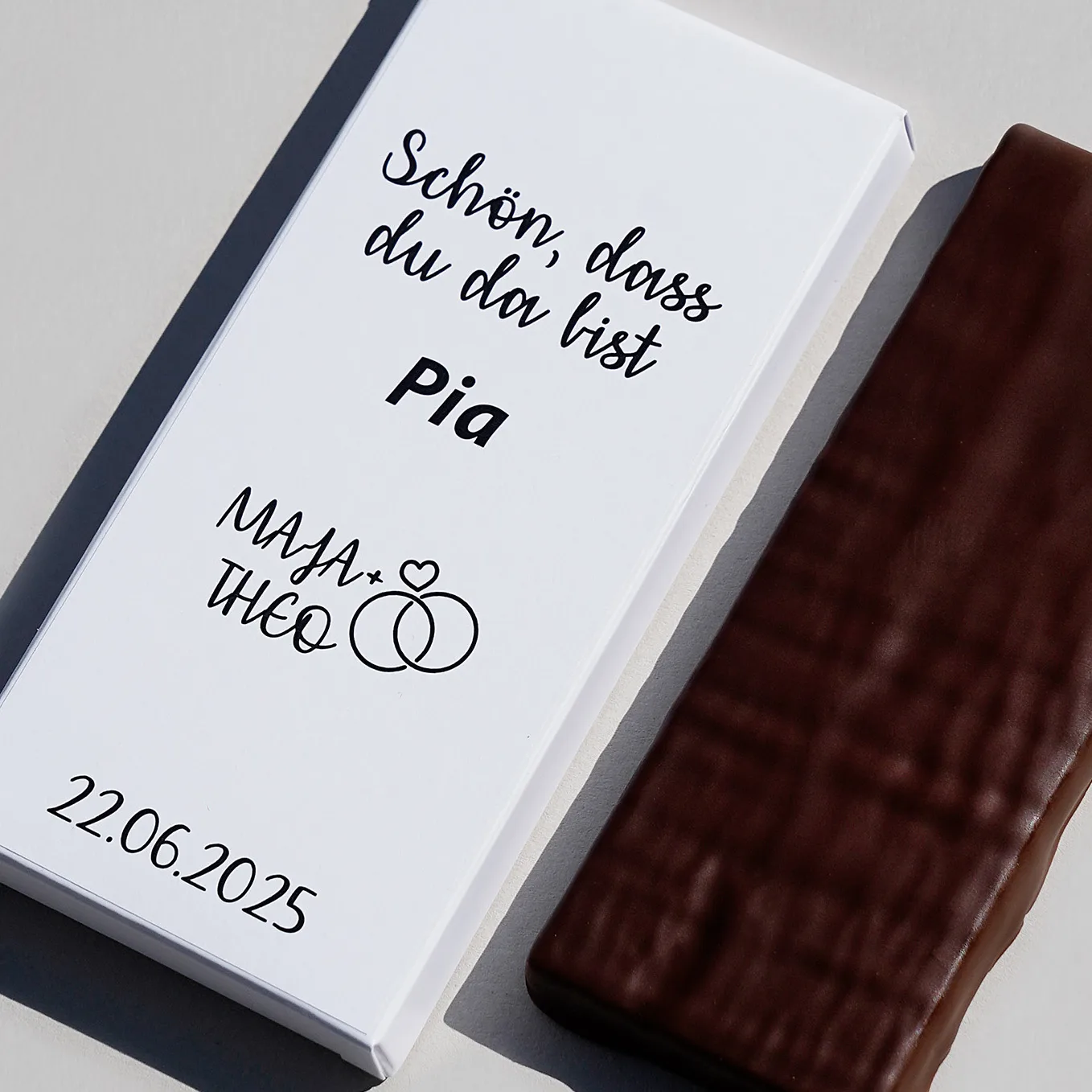 gefüllte Tafelschokolade in dunkler Schokolade neben einer Beispielverpackung als Namenskarte