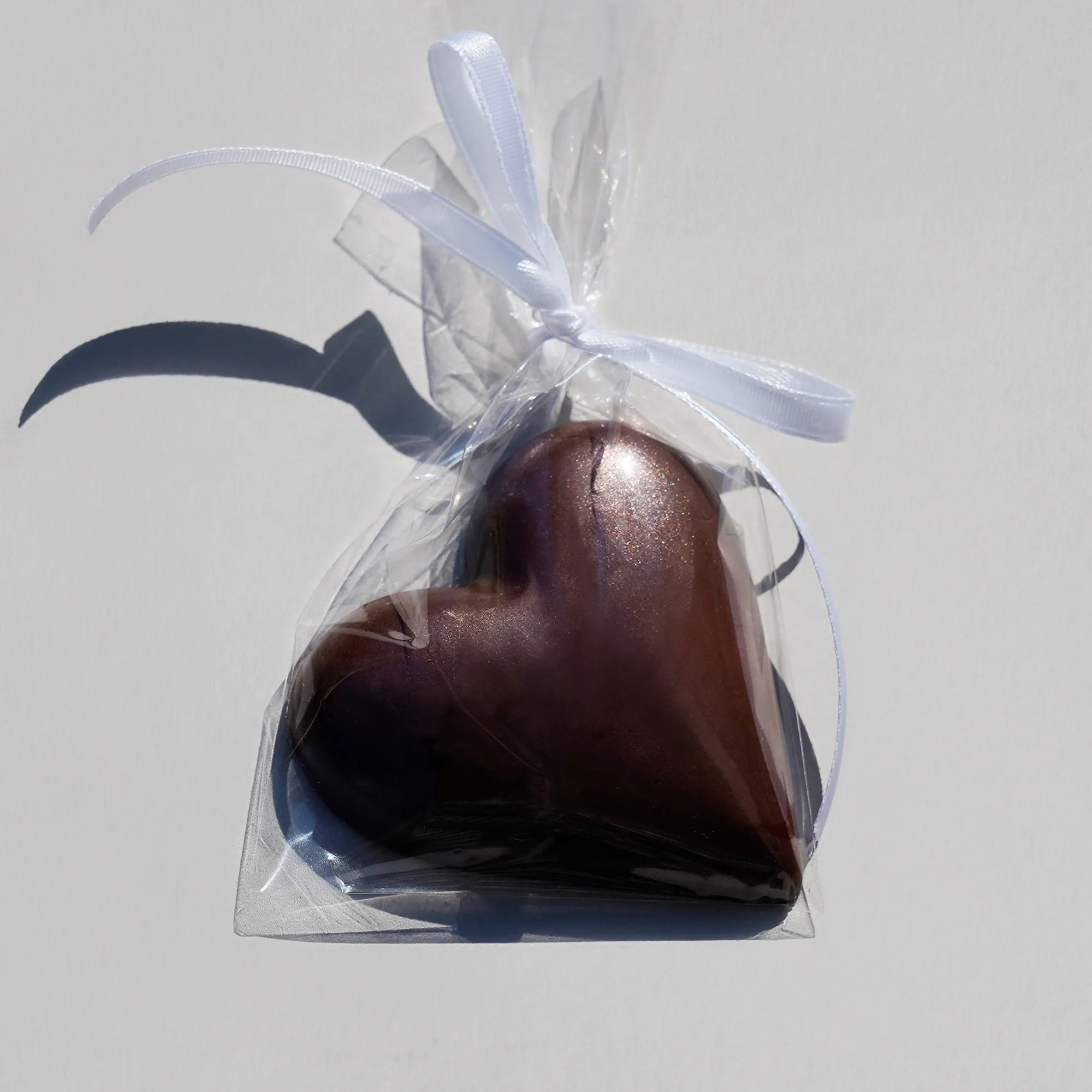Tafel in Herzform in dunkler Schokolade eingepackt in einen OPP-Beutel mit weisser Schleife als Beispiel für einen Hochzeitstisch