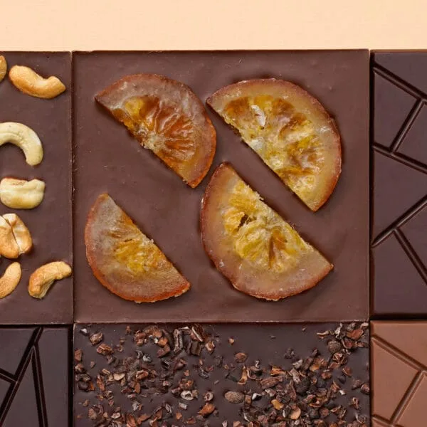 Schokoladentafeln, verschieden belegt von oben. Die Tafeln sind mi halbierten kandierten Orangenscheiben, Cashewkernen und Kakaosplittern belegt.