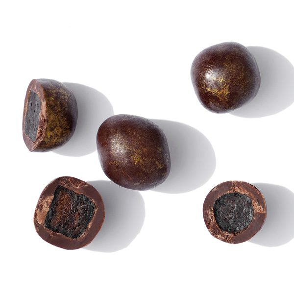 Cacao Pulpa-Bites auf weißem Hintergrund. Teilweise aufgeschnitten, dass man den Fruchtkern umhüllt von Schokolade sehen kann.